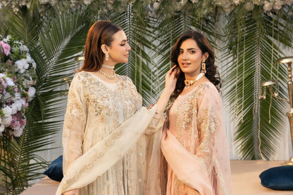 Two women in traditional outfits standing next to each other with a decorated background.